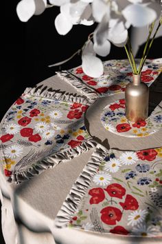 a vase filled with flowers sitting on top of a white table cloth covered tablecloth