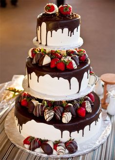 a triple layer cake with chocolate and strawberries on top is sitting on a table