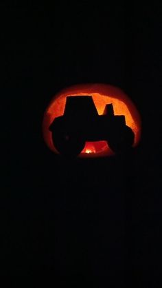 a pumpkin carved to look like a tractor in the dark