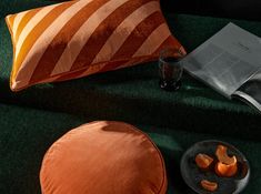 an orange pillow and some other items on a green surface with a book next to it