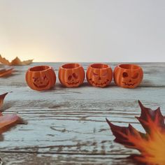 three pumpkin shaped cups sitting on top of a wooden table