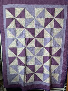 a purple and white quilt is hanging on the wall