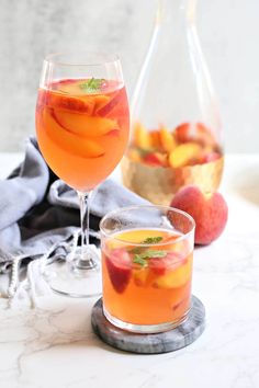 two glasses filled with liquid and fruit next to each other