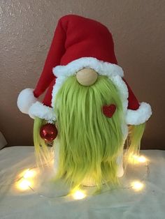 a green and yellow stuffed animal wearing a santa hat with lights on it's head