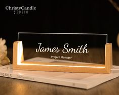 a wooden business card holder sitting on top of a table next to a white flower