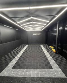 an empty hallway with black and white checkered flooring, lights and lighting fixtures