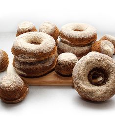 a wooden cutting board topped with donuts covered in powdered sugar