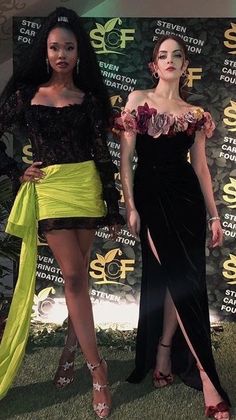 two women standing next to each other on a green carpet