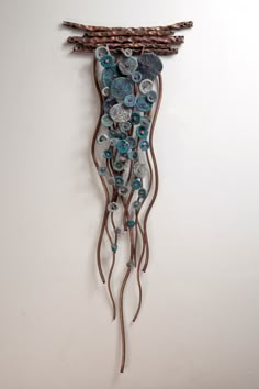 a metal wall hanging with buttons on it's side and branches in the middle