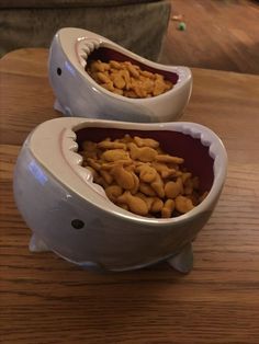 two bowls filled with food sitting on top of a wooden table next to each other