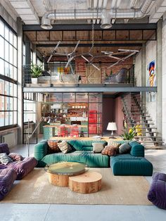 a living room filled with lots of furniture next to a fire place in a loft