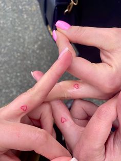 three people with pink fingernails and hearts on their fingers, holding each other's hands