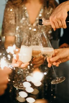 several people are toasting with wine glasses in front of sparklers and confetti