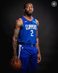 a man in a blue jersey holding a basketball and looking at the camera with a serious look on his face