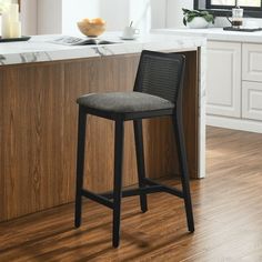 a black bar stool sitting in front of a counter top next to a wooden floor