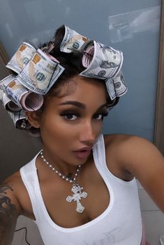 a woman with money tied to her head wearing a white tank top and pearl necklace