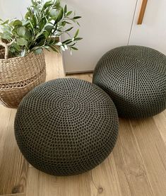 two round knitted poufs sitting on the floor next to a potted plant