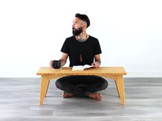 a man sitting at a table with a book and cup