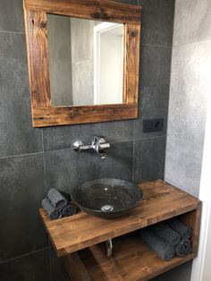 a bathroom sink sitting under a mirror next to a wooden shelf