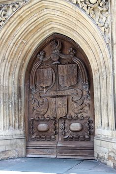 an ornate carved wooden door on the side of a stone building with arched doorways