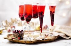 three glasses filled with red wine sitting on top of a wooden tray next to christmas decorations