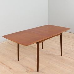 a wooden table sitting on top of a hard wood floor next to a white wall