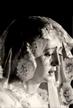 black and white photograph of a woman wearing a veil with flowers on her head, looking off to the side