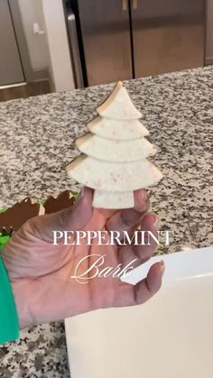 a hand holding a piece of food with a christmas tree on it