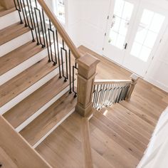 a wooden staircase with black railing and handrails in a white house or home