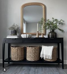 a black console table with baskets and a mirror