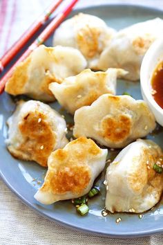 some dumplings are sitting on a plate with chopsticks