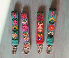 three lanyards with flowers on them are sitting next to each other and one has a metal hook