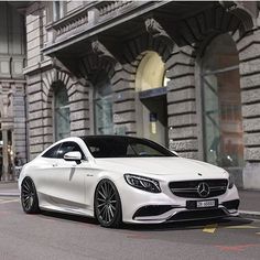 a white mercedes s - class parked on the street in front of an old building