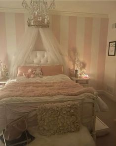 a bedroom with a bed, chandelier and pink striped wall paper on the walls