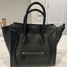 Selling My Pristine Celine Mini Luggage Bag. This Is An Authentic Celine Smooth Calfskin Mini Luggage In Black. This Chic Travel Tote Is Crafted Of Calfskin Leather In Black. The Bag Features Rolled Leather Top Handles, Expandable Sides, A Facing Zipper Pocket And A Top Overextended Zipper. This Opens To A Spacious Black Interior With Zipper Pocket. Included: Handbag, Dust Bag And Receipt. Purchased From Celine At Montaigne, Paris. Smoke And Pet Free Home. Selling As It’s A Bit Large For My Petite Frame. Celine Travel Bag, Sac Celine Luggage, Celine Mini Luggage Bag, Celine Black Crossbody Bag, Celine Micro Luggage, Celine Mini Luggage, Mini Luggage, Home Selling, Luggage Bag