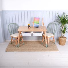 a wooden table with four chairs and a potted plant on the floor next to it