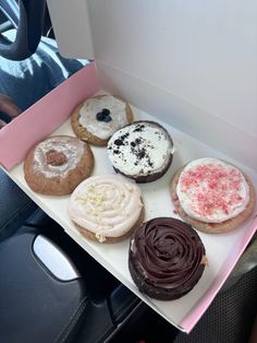 a box filled with assorted donuts on top of a car seat