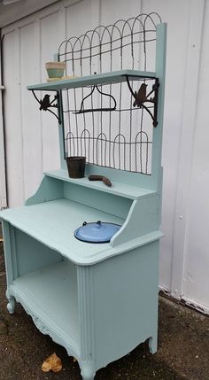 an old blue desk with a birdcage on it's top and shelves