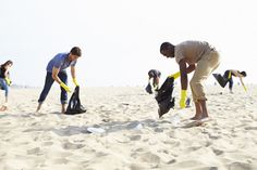 several people on the beach with their feet in the sand and one person holding a bag