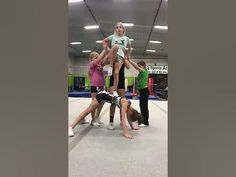 a group of people standing around each other on top of a trampoline in a gym