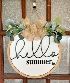 a sign that says hello summer hanging on a door with greenery and burlocks