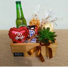 a wooden box filled with assorted snacks and beer next to a bottle of wine