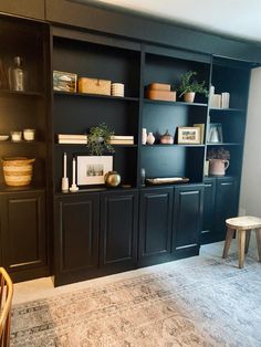 a living room with black bookcases and other items on the shelves in front of it