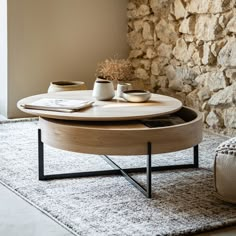 a coffee table with two cups on it in front of a stone wall and rug