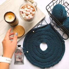 a person is knitting on a table with yarn and other crafting supplies around it