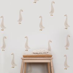 a small stool in front of a white wall with a pattern of ducks on it