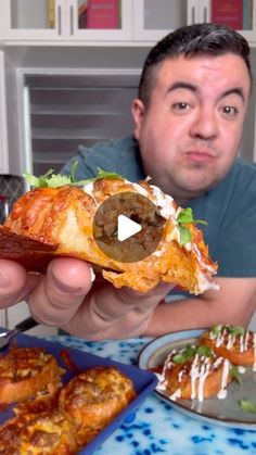 a man holding up a piece of food in front of some other foods on plates