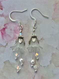 a pair of white flower earrings with crystal beads and swarongs on them