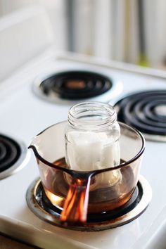 a glass jar with some liquid on top of it sitting on a stove burner