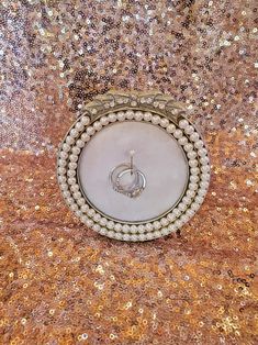 a white brooch with pearls and a diamond ring on it's center piece